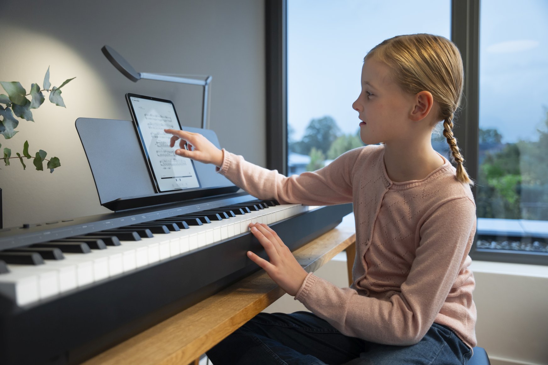 Girl playing Kawai ES60 while using iPad